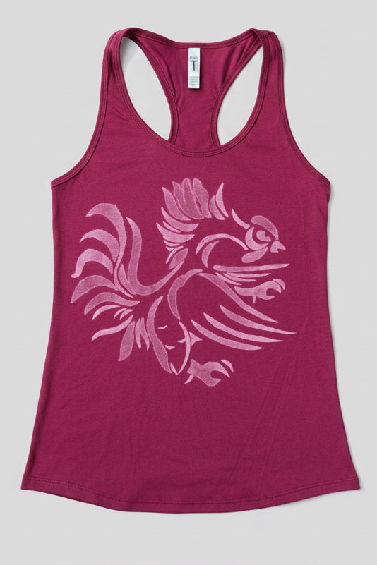 A women's racerback tank top in a garnet color, featuring a large light distressed graphic of a stylized gamecock on the front. The tank top is displayed flat against a solid light gray background.