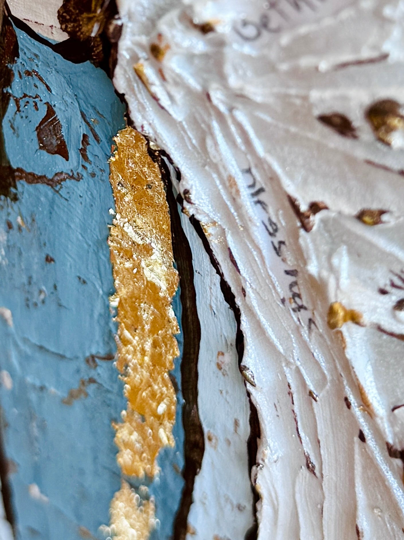 Close-up of a textured angel painting with gold leaf and custom prayers

