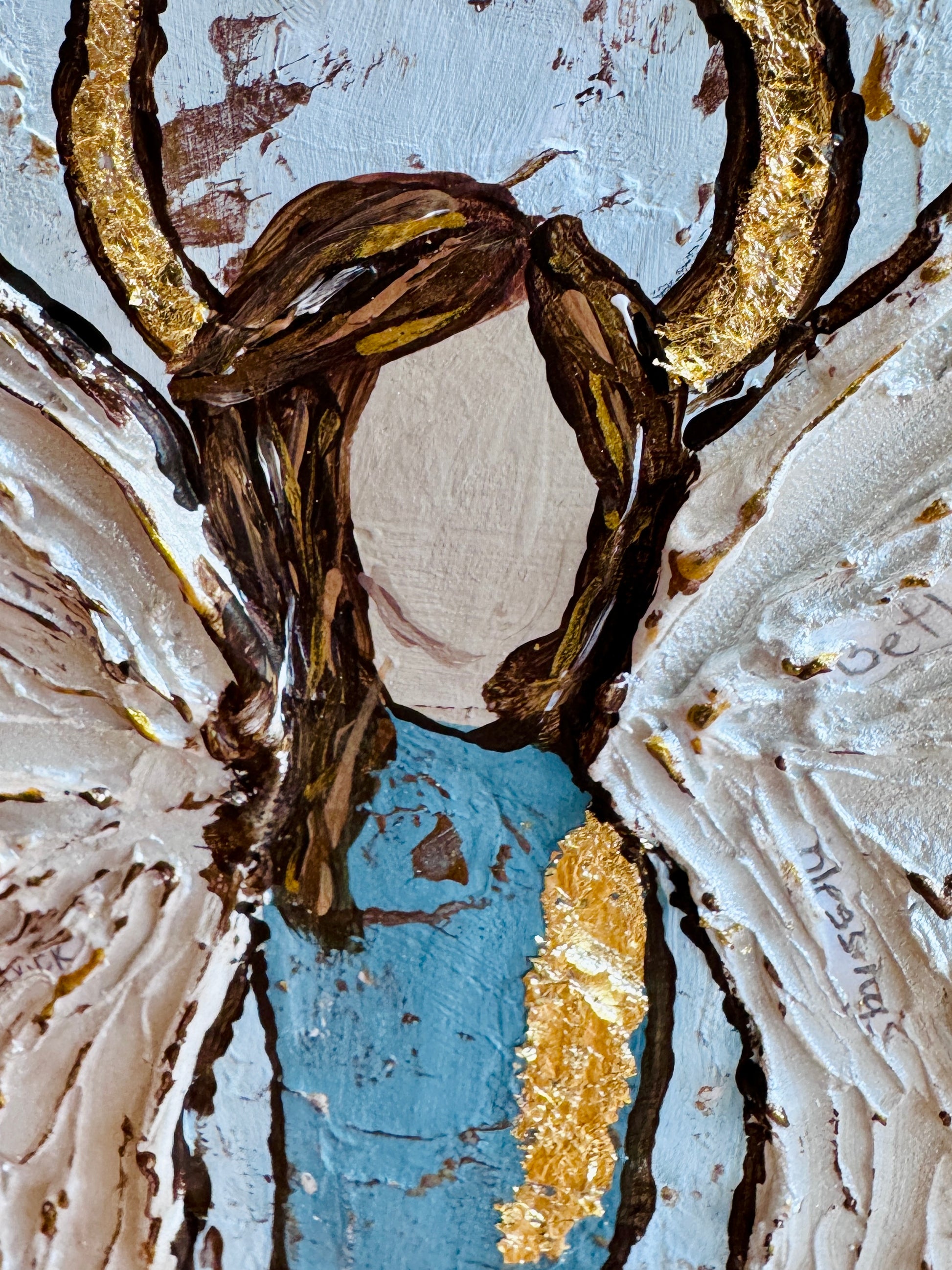 angel artwork with brown, gold, and blue colors with textured angel wings and hidden prayers.

