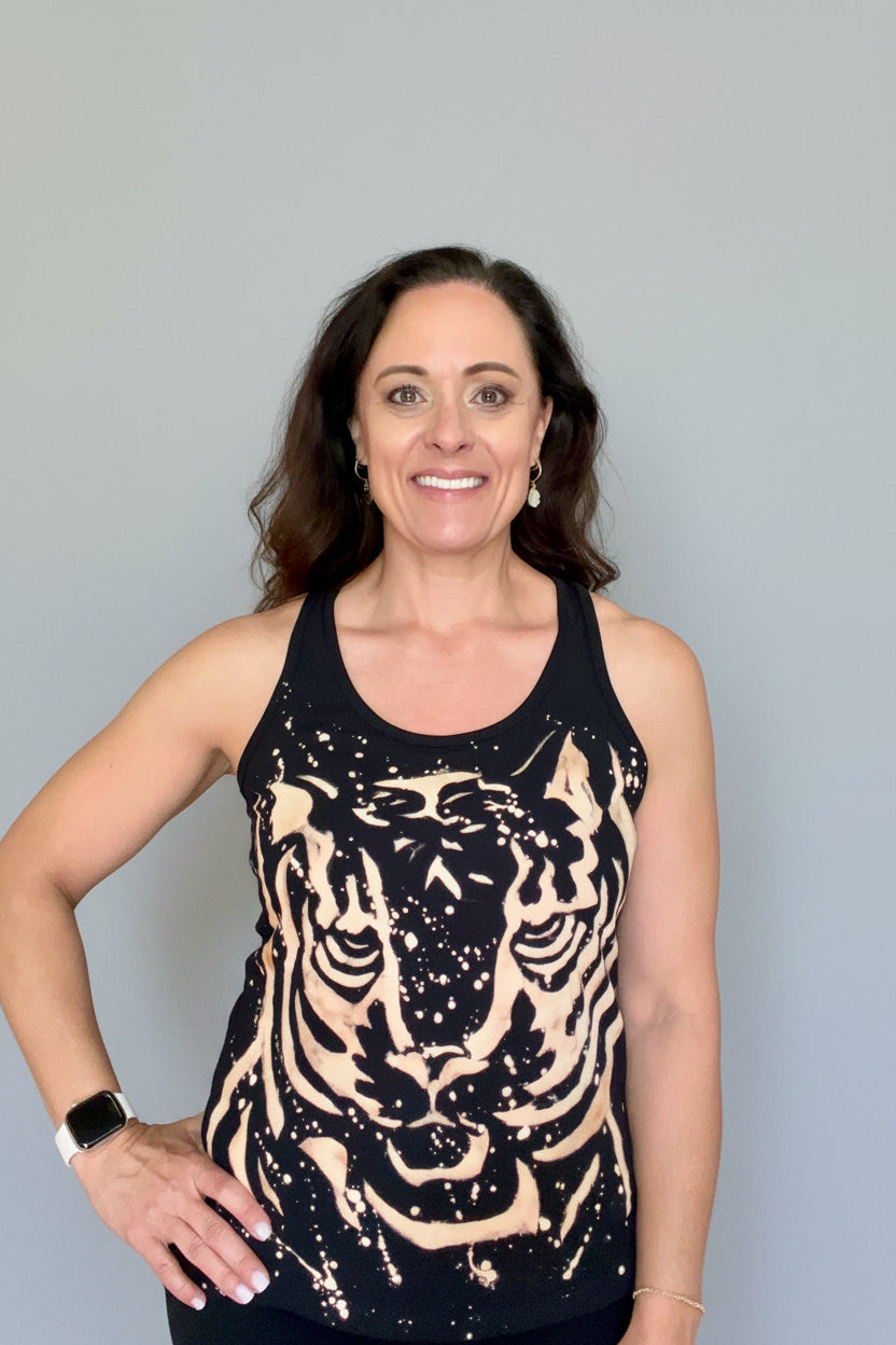 Woman wearing a black tank top with a tiger design in a home setting